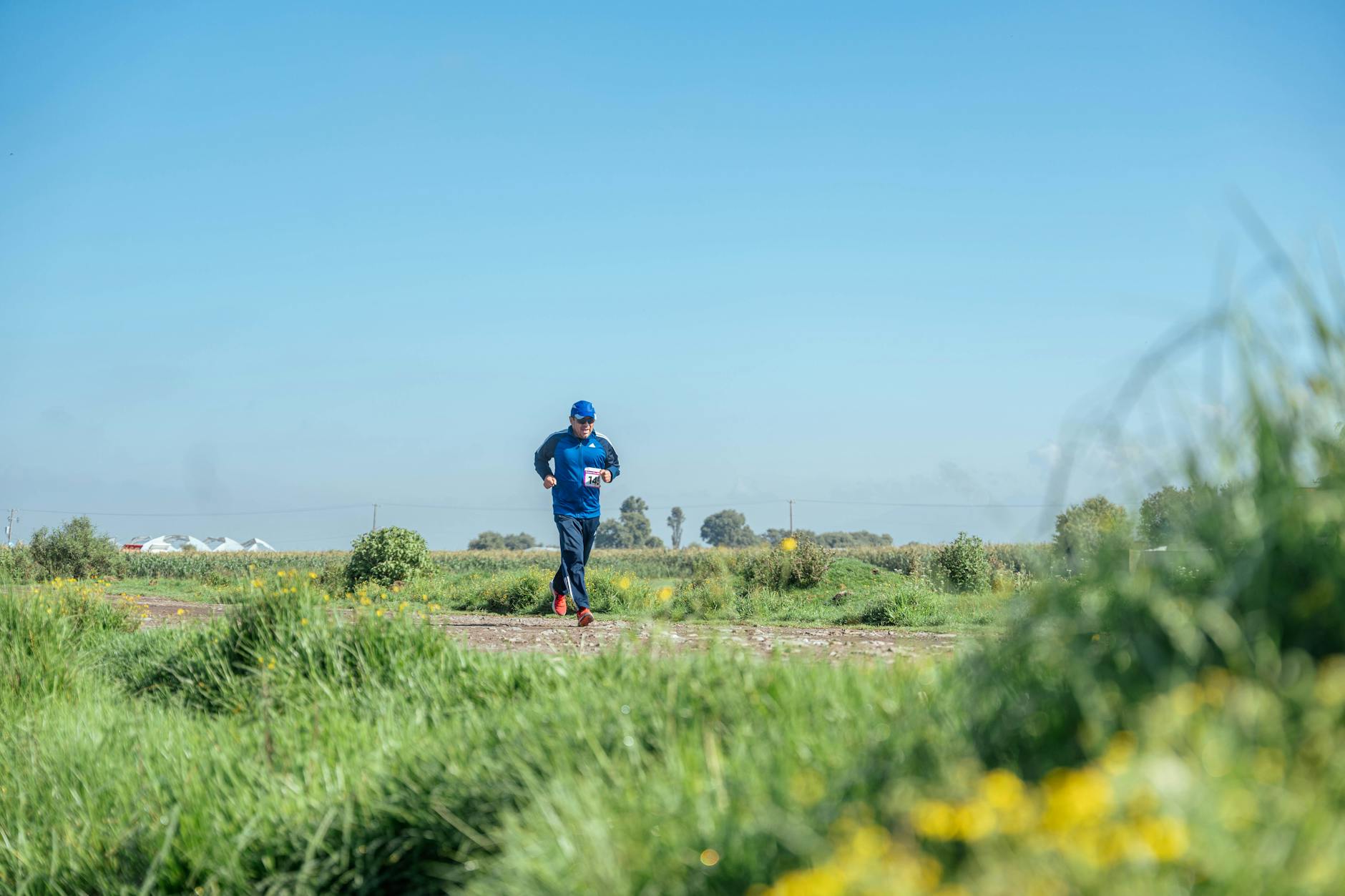 Biegacz wracający do formy biegnie po wiejskiej, trawiastej ścieżce